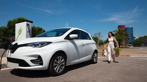 Electric Vehicle at an EV charging point lady approaching the car with bags of shopping - Top 6 Tips for Maximising Your EV's Range