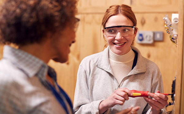 2 people, one holding a tool, and wearing Goggles, representing Schneider Electric apprenticeship programme